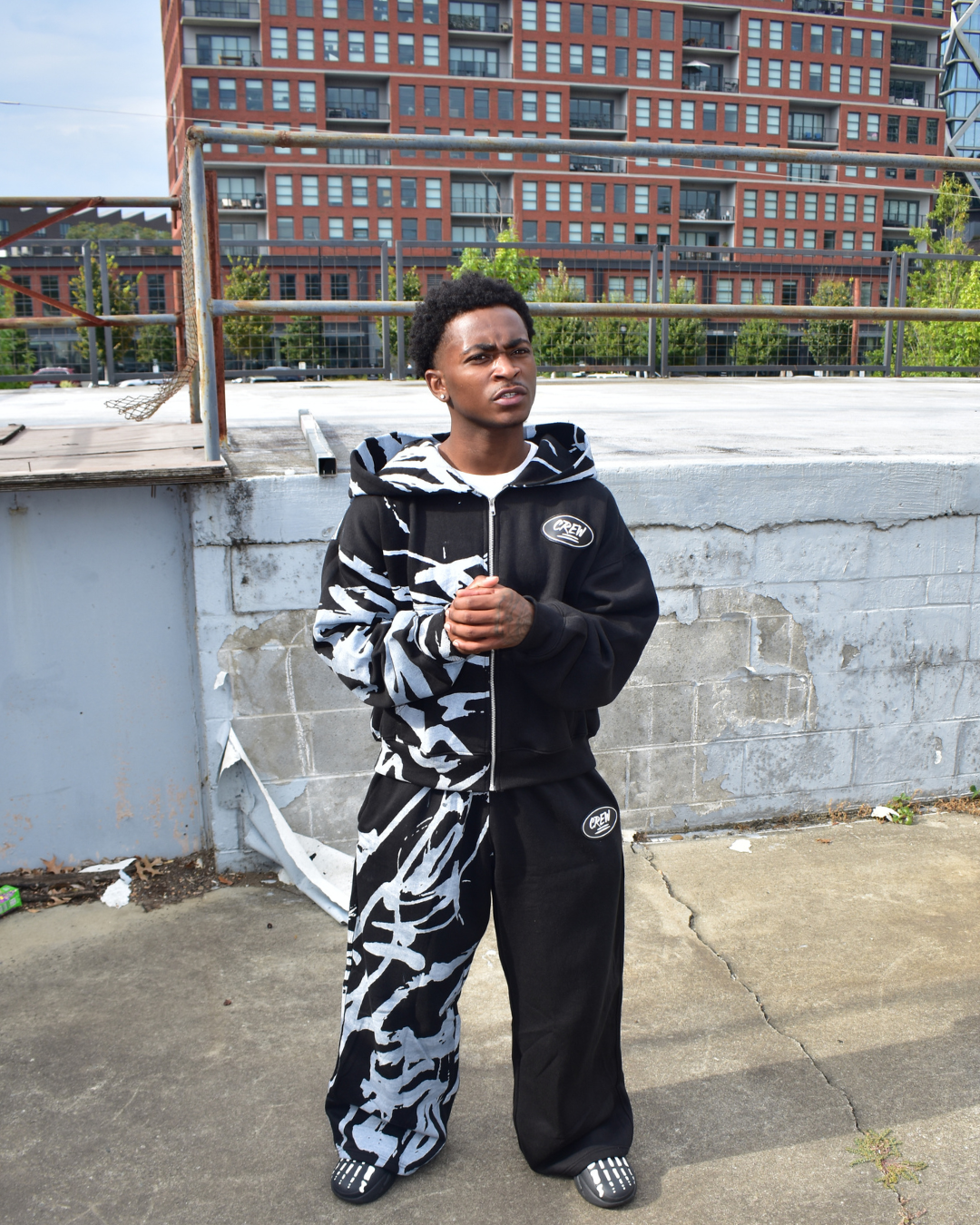 Model wearing a black and white Graffiti tracksuit on a rooftop with buildings in the background
